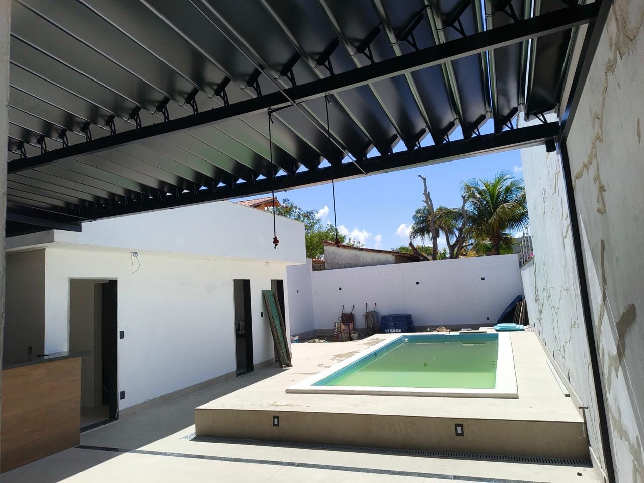 Cobertura retrátil preta com lâminas abertas sobre área gourmet com piscina