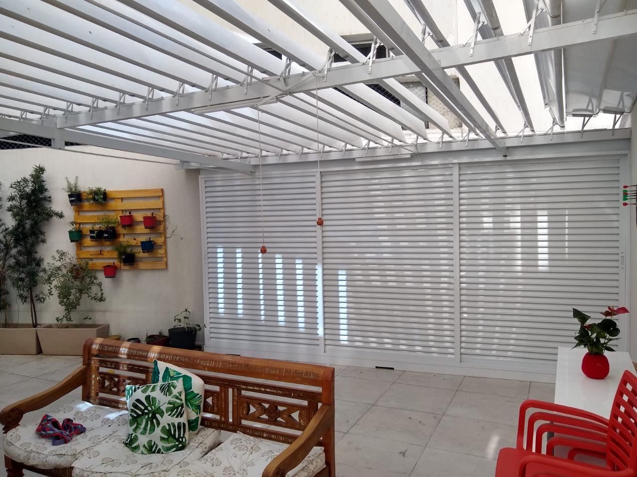 Área externa com cobertura retrátil branca e móveis